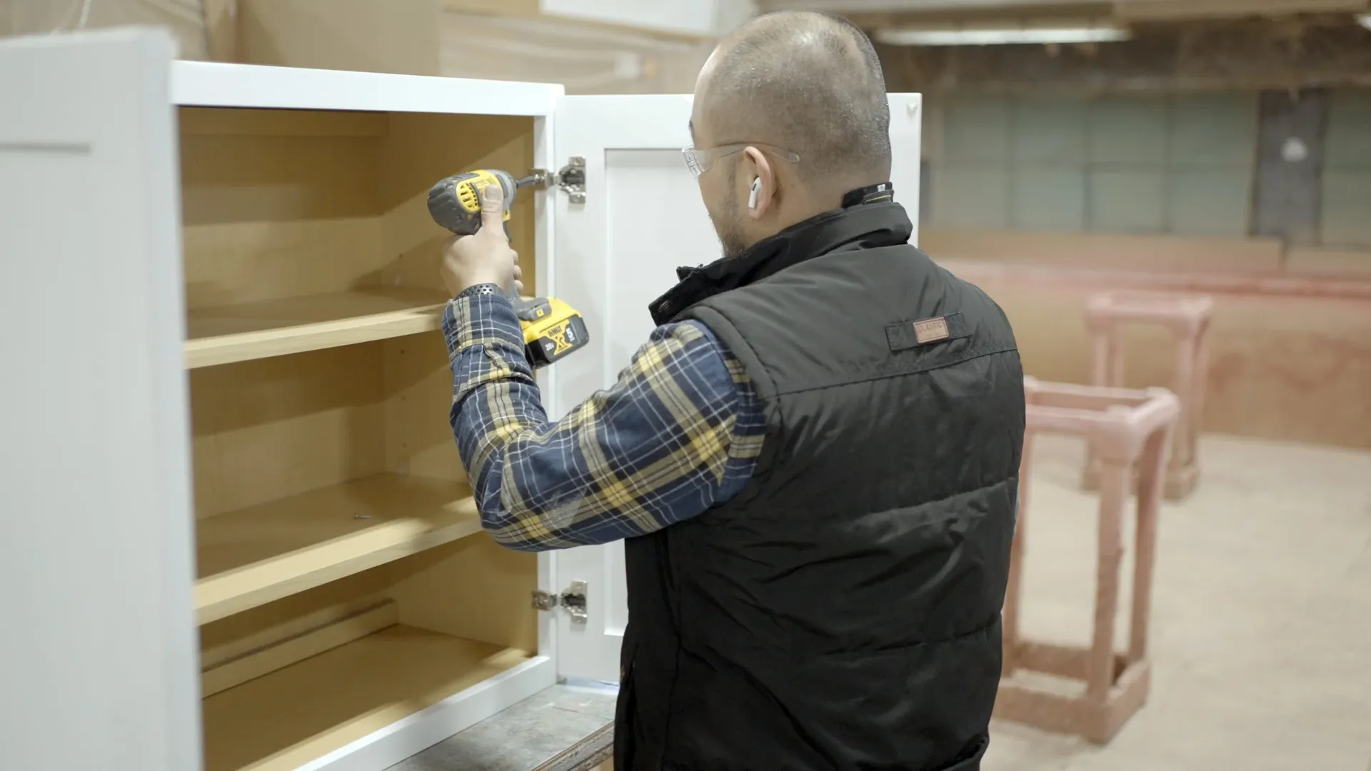 A worker uses a drill to attach a kitchen cabinet door.